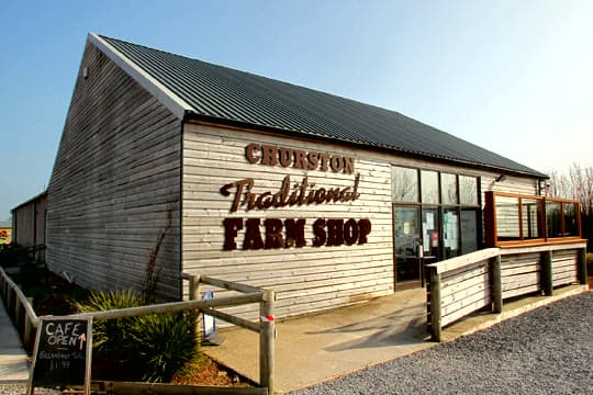 The timber-clad Churston Traditional Farm Shop building on the Dartmouth Road, café-open board by the gate